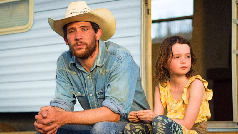josh o connor sits with his character s daughter on the front porch of their mobile home in rebuildi